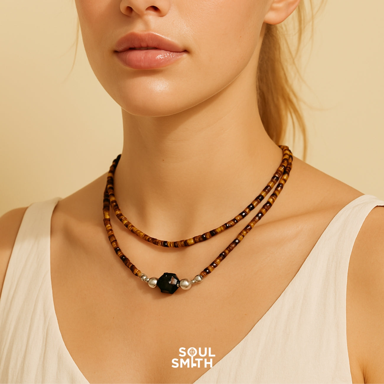 Woman wearing layered Soulsmith tiger’s eye bead necklace with black obsidian centerpiece and silver accents, designed for grounding, protection, and inner strength.