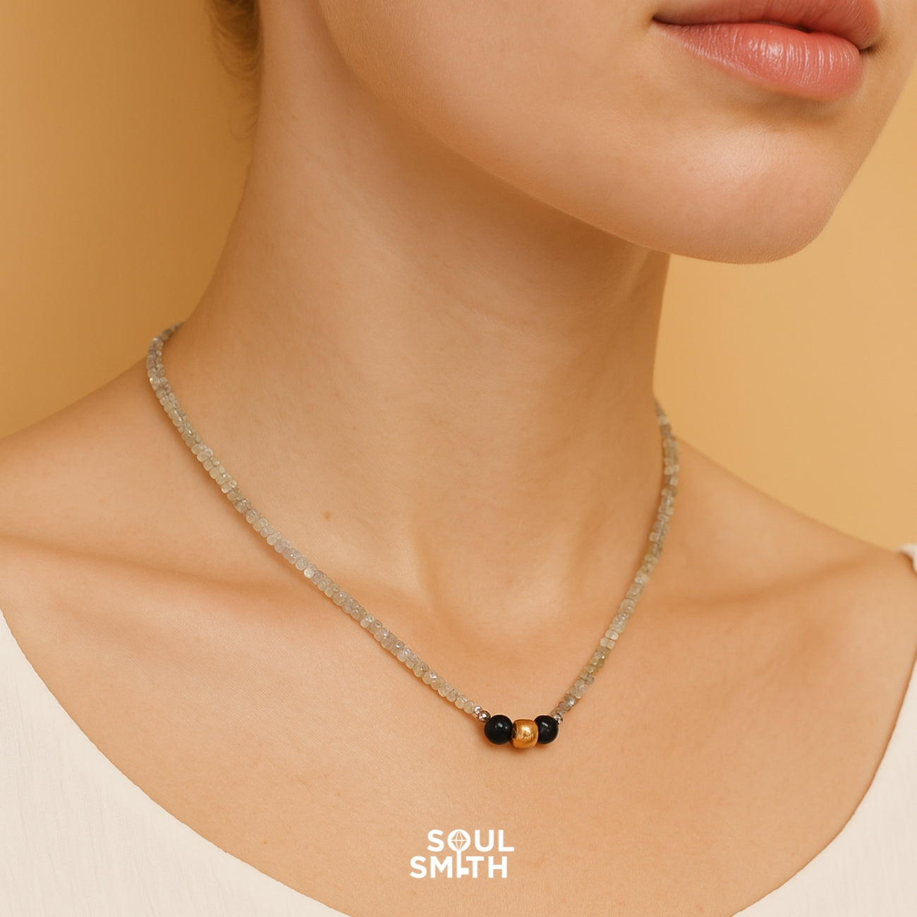 Woman wearing Soulsmith handmade necklace with faceted labradorite beads, black onyx, and gold accent, crafted for protection and spiritual insight.