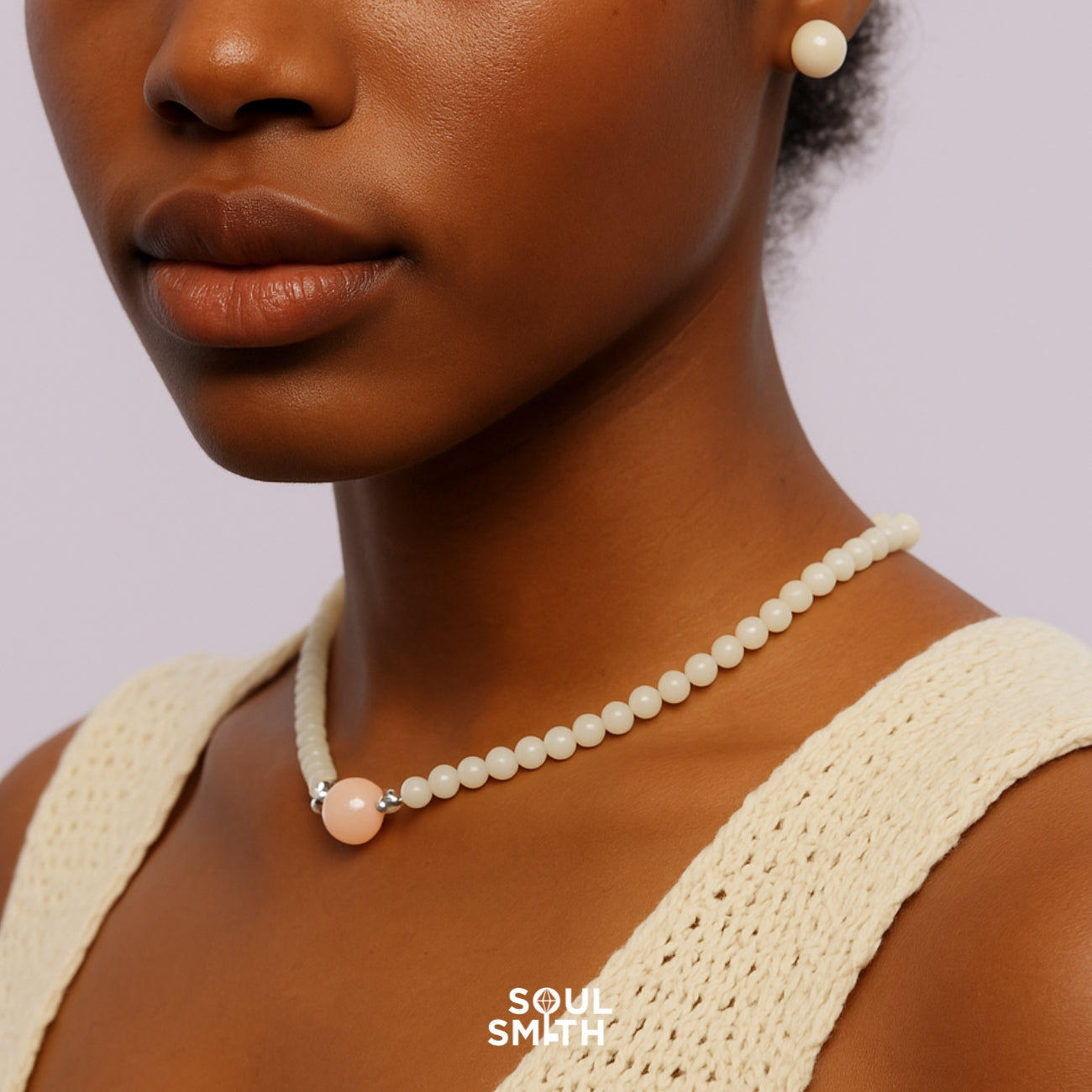 Model wearing a Pink Morganite charm necklace with soft ivory beads, paired with matching earrings. The jewelry is styled in a minimal, feminine look, part of the Soulsmith collection.