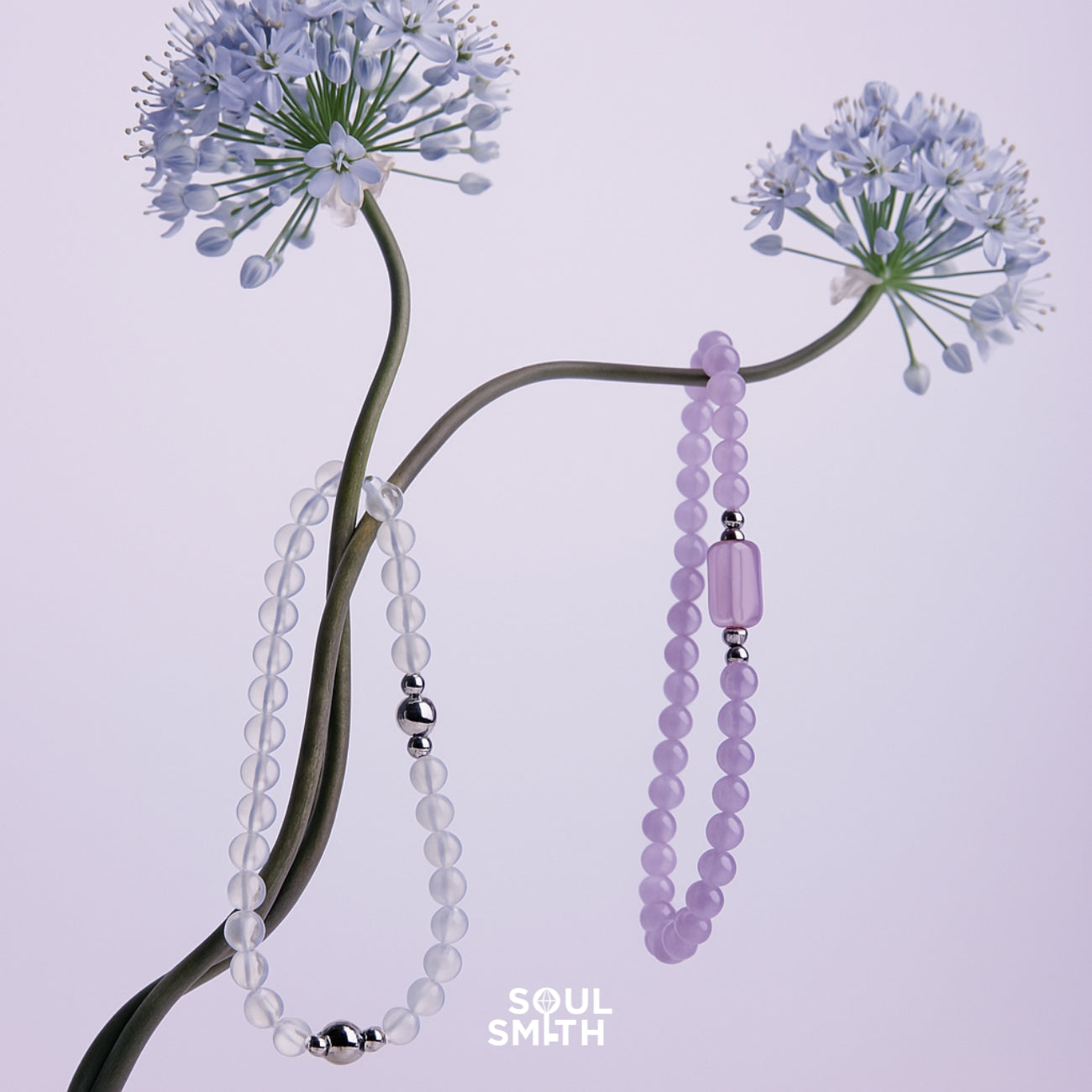 Minimalist display of crystal healing bracelets in white quartz and lavender jade on delicate flower stems – ethereal handmade jewelry by Soul Smith for chakra balance and energy alignment