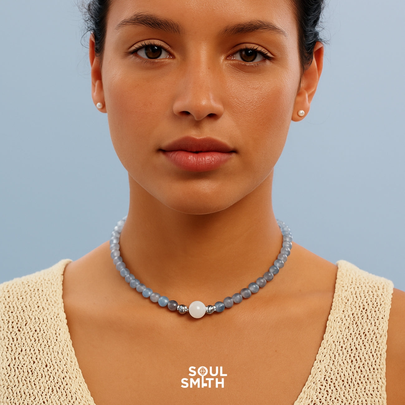 Throat chakra necklace with aquamarine and moonstone beads, styled on model in cream knit top.