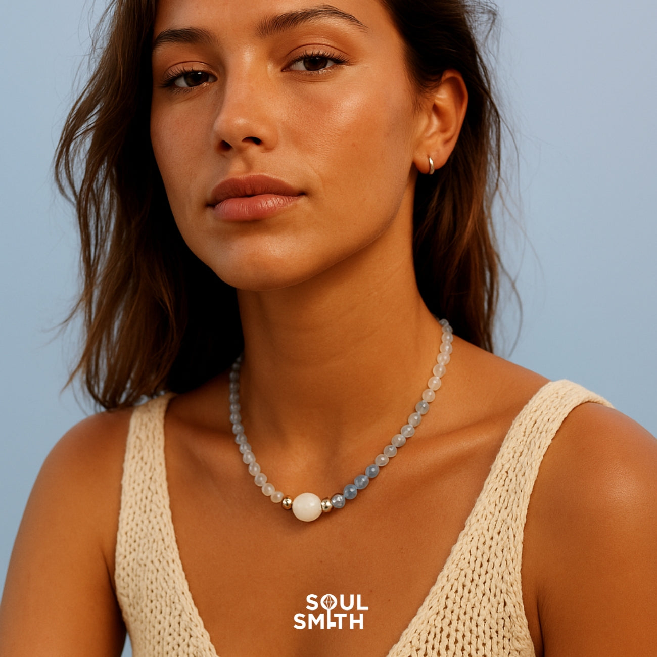 Moonstone and aquamarine necklace for balancing the throat chakra, worn with a cream knit top.