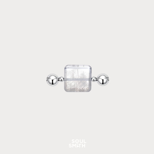 Square-cut Blue Needle Crystal charm flanked by polished silver beads, showcasing delicate thread-like inclusions in a translucent, icy base — an ethereal element from the Soulsmith SoulLinks collection.
