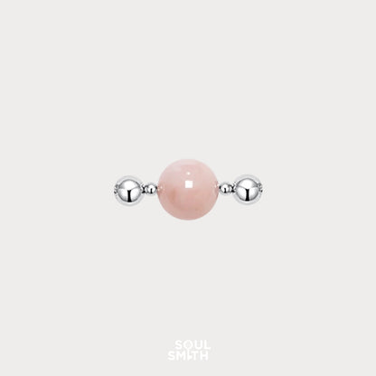 Polished Pink Morganite charm bead flanked by two shiny silver-toned spacers, set against a light grey background.