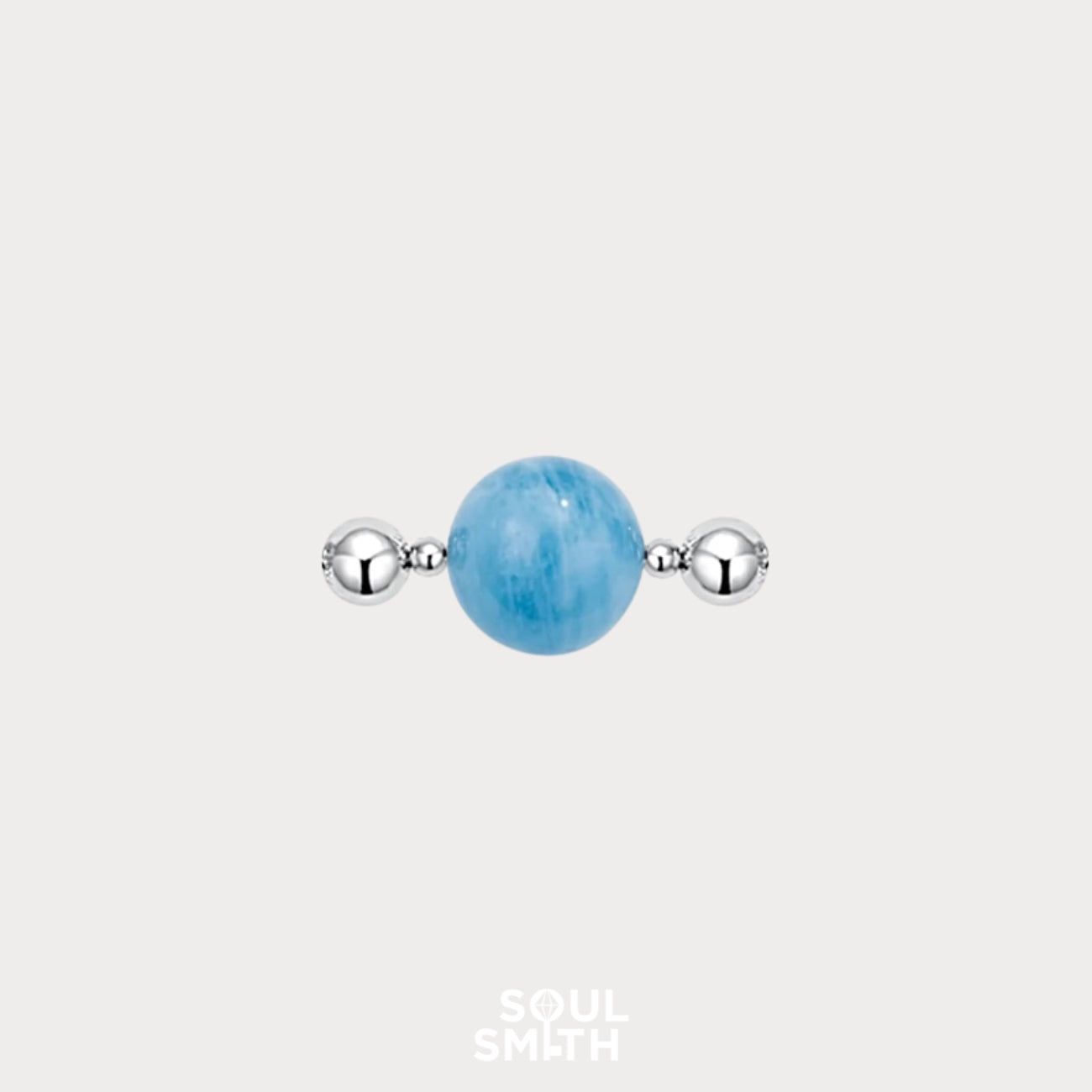 Soulsmith charm featuring a polished aquamarine gemstone centered between two reflective silver beads, set against a light grey background.

