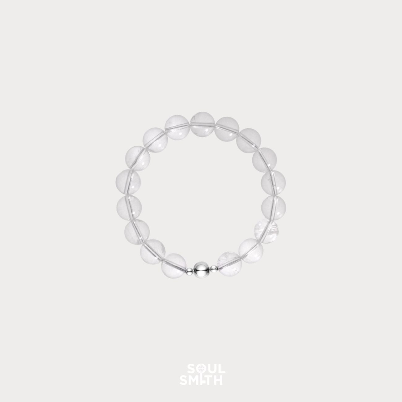 Minimalist clear quartz crystal bead bracelet with round polished stones and a silver magnetic clasp, displayed on a light neutral background 
