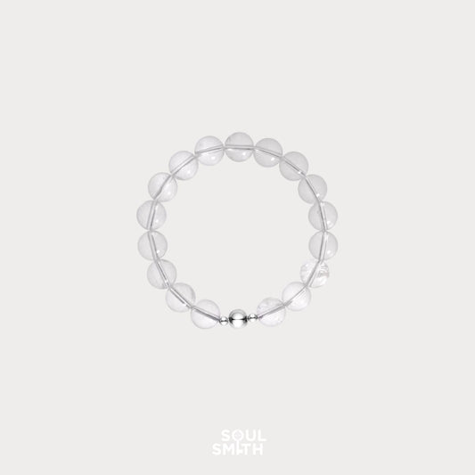 Minimalist clear quartz crystal bead bracelet with round polished stones and a silver magnetic clasp, displayed on a light neutral background 
