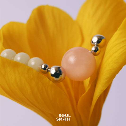 Pink Morganite charm with silver-toned spacer beads, resting delicately inside a vibrant yellow flower petal, styled for Soulsmith.
