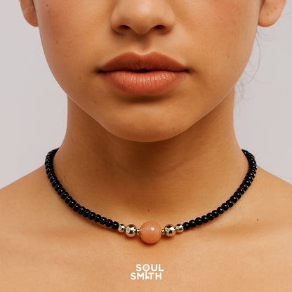 Close-up of orange moonstone and black crystal choker for sacral chakra empowerment.
