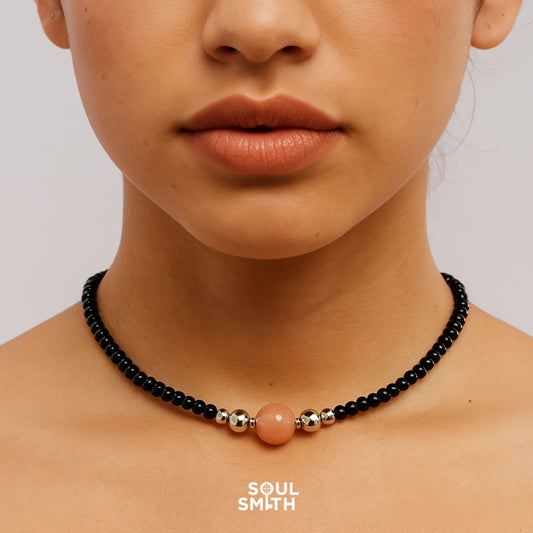 Close-up of orange moonstone and black crystal choker for sacral chakra empowerment.

