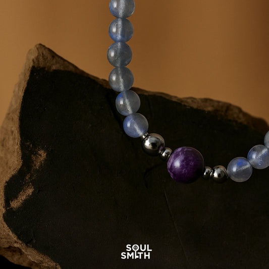 Charoite and kyanite chakra necklace on black stone background for crown and throat chakra balance – SoulSmith handcrafted jewelry
