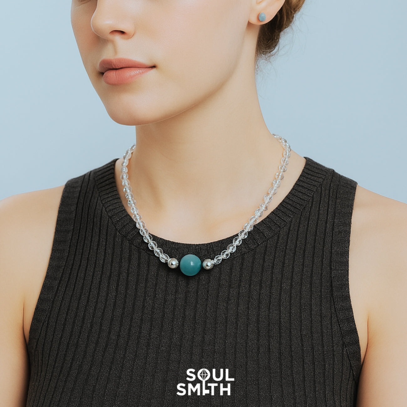 Model wearing a ribbed black tank top and a double-strand clear quartz necklace with a bold dark teal Berylite charm centerpiece, accented by silver beads — Soulsmith signature SoulLinks style.

