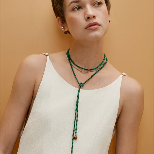 Model wearing SoulSmith Soullinks malachite rope necklace styled in a layered Y-knot wrap, featuring tiger eye accents – a versatile crystal necklace for grounding and heart chakra energy.